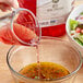A person pouring Colavita red wine vinegar into a bowl of salad.