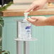 A person using a Purell hand sanitizer pump on a bottle of Purell Advanced Foam Hand Sanitizer.