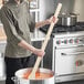 A man holding a Choice wood paddle in front of a stove.