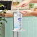 A person using a Purell hand sanitizer pump on a table.