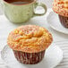 Two David's Cookies French Toast Muffins on white plates with a cup of coffee on a table.