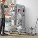 A man using an Avantco commercial floor mixer with a metal bowl.