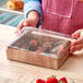 A person holding an Enjay wood laminated box of chocolate covered strawberries.