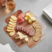 An Enjay wood laminated box filled with cheese and crackers on a table.