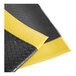A black anti-fatigue mat with yellow borders and a diamond plate texture.