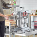 A man using an Avantco commercial stand mixer to grind meat.