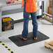 A man in an orange vest standing on a black Lavex Diamond Star anti-fatigue mat.