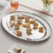 An Acopa stainless steel oval platter with a burrito and tortilla chips on it.