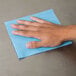 A hand using a blue Chicopee Veraclean wiper on a blue surface.