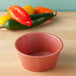 A red HS Inc. paprika ramekin on a wood table.