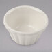 A close-up of a Hall China flared ivory ramekin on a white surface.