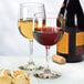 A close-up of a Libbey Bristol Valley wine glass filled with red wine on a table next to a bottle of wine.