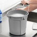 A person washing a Lavex bucket on a counter.