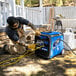 A man in overalls using a DuroMax portable generator indoors.