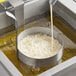 A Carnival King stainless steel funnel cake mold ring being poured into on a counter.