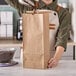 A woman pouring coffee into a brown paper bag on a counter.