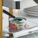 A can of Sterno ethanol gel chafing fuel being lit with a lighter under a chafing dish.