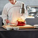 An Avantco wood cutting board on a table with a chef slicing a piece of meat.