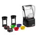 The Blendtec Stealth 895 blender with yellow, green, and purple plastic bowls and lids.