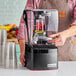 A man using a Blendtec Stealth 895 blender on a counter in a smoothie shop.