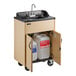 A portable hot water hand sink with a maple laminate cabinet, single basin, and storage space for water containers.
