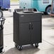 A black portable hot water hand sink with a laminate cabinet, single basin, and wheels for mobility.