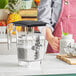 A woman using a Blendtec blender with a clear jar filled with a white smoothie.