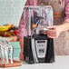 A person using a Blendtec Connoisseur 825 blender to make a smoothie.