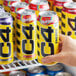 A close-up of a hand holding a yellow C4 Energy Skittles energy drink can with black and red lettering.