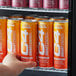A person's hand holding a peach and white C4 SMART Energy drink can.