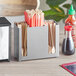 A silver stainless steel flatware and chopstick organizer on a counter with chopsticks inside.