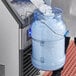 A person pouring ice from a large container into a round ice tote.