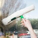 A hand holding a Unger green ThePad StripWasher on a window.