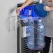 A woman using a blue Vigor ice tote lid to pour ice into a container.