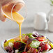 A hand pouring AAK Select French Dressing into a bowl of salad.