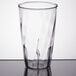 A Carlisle clear polycarbonate tumbler on a white table.