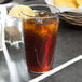 A Carlisle clear polycarbonate tumbler filled with iced tea, ice, and a lemon slice.