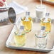 A person pouring white liquid into Acopa glass votive jars on a tray.
