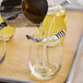 A person pouring liquid into a glass with a straw using an Acopa Bubble Glass Votive Candle Holder.