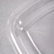 A clear plastic Sabert dome lid on a clear plastic container with a curved edge.