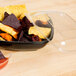 A bowl of chips with a Sabert clear plastic lid and a plastic container of sauce.