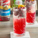Two glasses of red liquid with cranberries and orange slices.