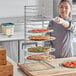 A woman holding a Choice pizza pan rack with pizzas on it.