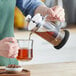 A hand pouring coffee into a glass from an Acopa French coffee press.