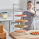 A woman holding a metal tray with 11 pizzas on it.