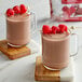 A glass mug of Land O Lakes Raspberry and Chocolate hot cocoa with raspberries on top.