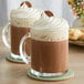 Two mugs of Land O Lakes peanut butter and chocolate hot cocoa with whipped cream and chocolate drizzle.