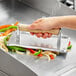 An 8" x 4" aluminum steak weight on a bed of vegetables.