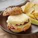 A cheeseburger with Follow Your Heart Vegan Sliced Pepper Jack Cheese and chips on a plate.