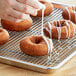 A person pouring white icing on a Pillsbury Taste Best cake donut.